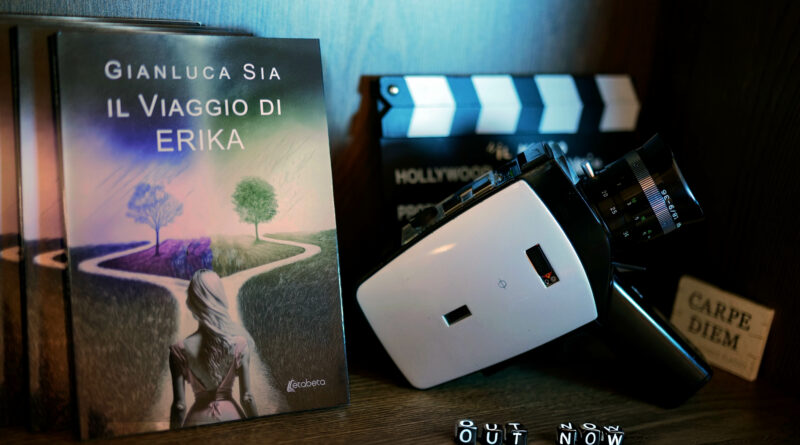 L'immagine mostra la copertina del romanzo "Il viaggio di Erika" affiancata da una cinepresa e un ciak. Questa composizione evidenzia come la storia del libro sia un'estensione e un seguito del film indipendente "Io resto qua", anch'esso scritto da Gianluca Sia